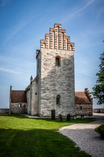 Datum: 2014:09:05 16:17:21 Højerup Kirke stammt aus dem 12. Jahrhundert. Bei ihrer Erbauung lag sie noch etwa 50 Meter von der Kliffkante entfernt. Durch die fortwährende Erosion des Kliffs rückte die Kante im Laufe der Jahrhunderte indes immer näher und im Jahre 1928 brach der Chorraum der Kirche ab und stürzte in die Tiefe. Seither wird mit verschiedenen Küstensicherungsmaßnahmen eine weiterer Abbruch des Kliffs an dieser Stelle zu verhindern versucht.
